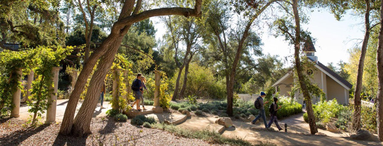 Students walking along garden path in front of Voskuyl Chapel.