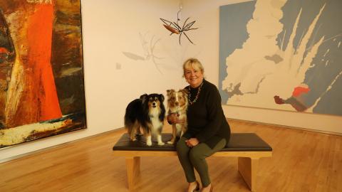 Judy sitting with her mini Aussies, Tucker and Tilly, in the gallery.