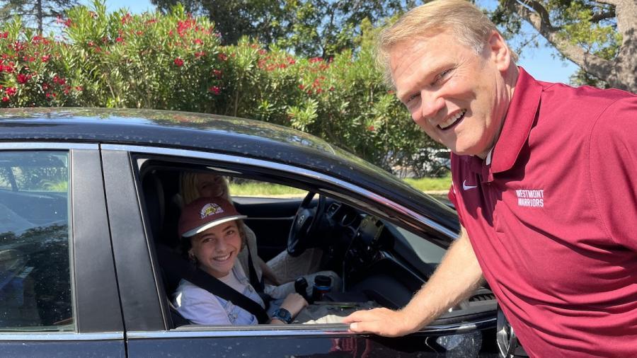 President greeting students as they first arrive to campus in their cars.