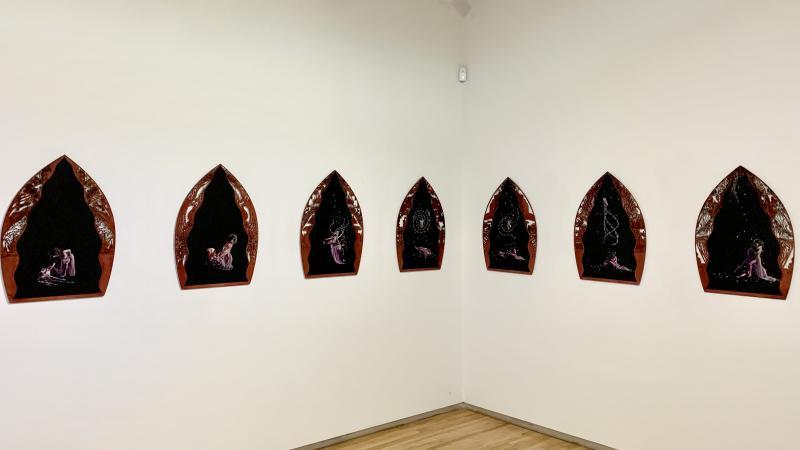 7 black and red wood panels hung in the gallery