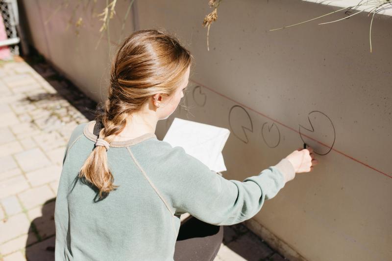 Student sketching outlines for a mural