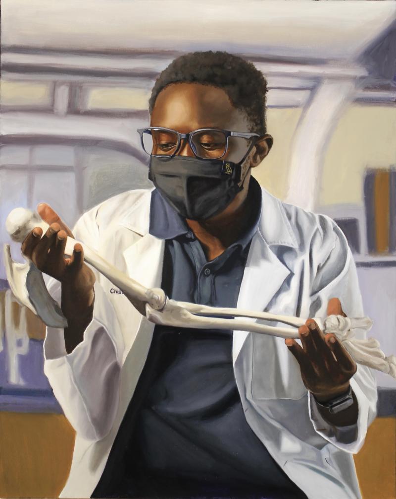 man in mask holding an arm bone in a lab