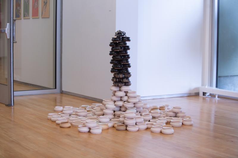 sculpture of black and white ceramic bowls piled together with nickels on top
