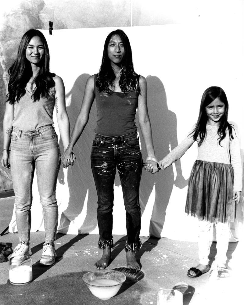 photo of 3 figures standing and holding hands