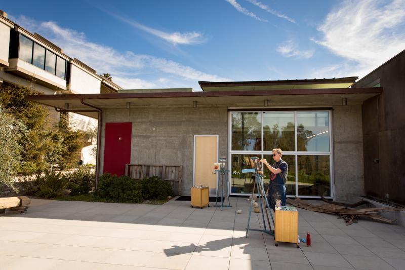 Art student painting on easel outside Adams Center