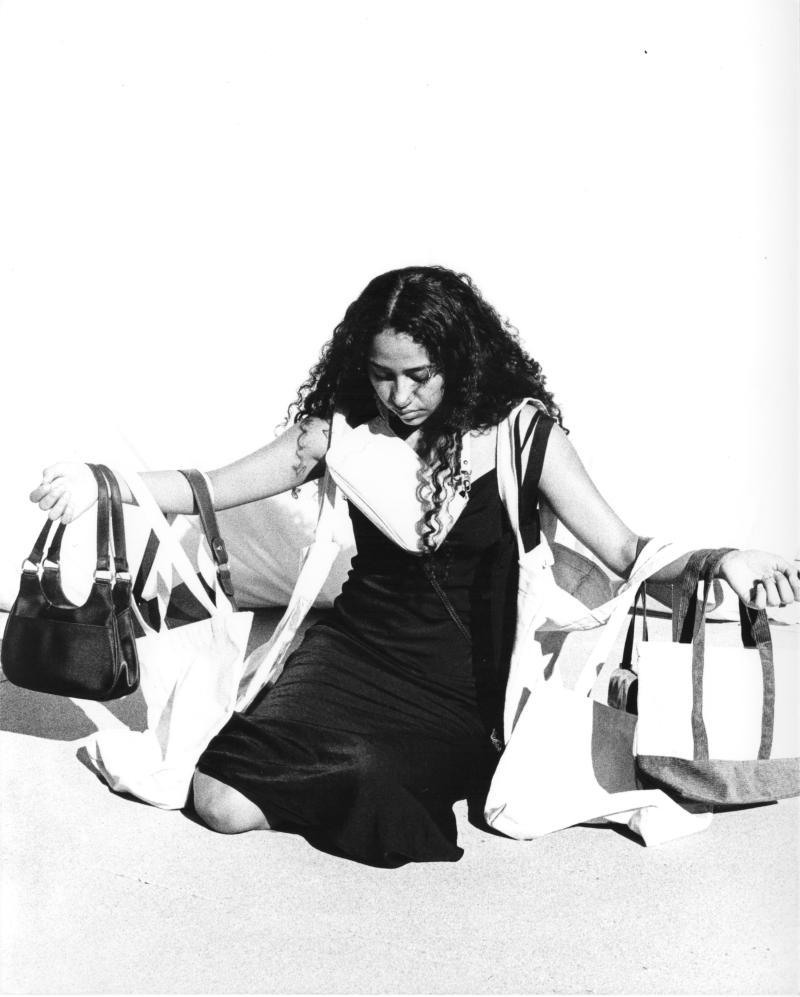 figure with outstretched arms holding handbags