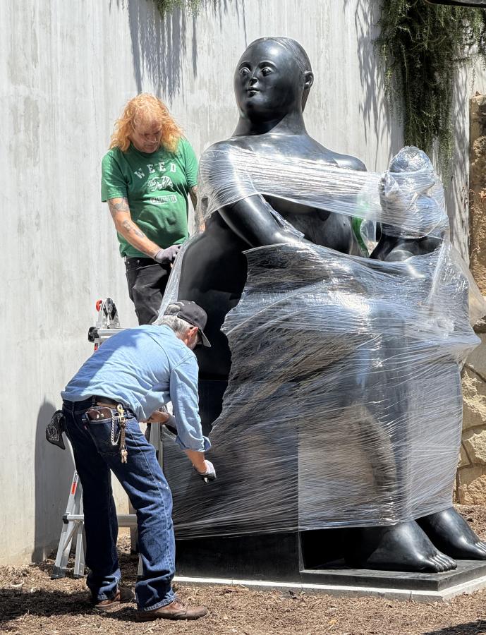 Workers unwrap the Botero sculpture at its new location