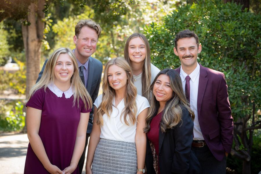 Group of 2 men and 4 women dressed nicely, smiling at the camera.