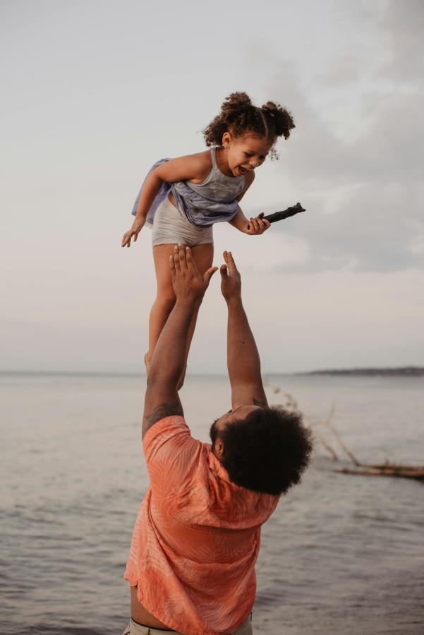 father throwing daughter in the air at beach